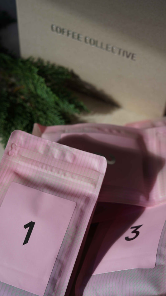 Pink coffee bags with numbers positioned in front of 'Coffee Collective' branded Advent Calendar